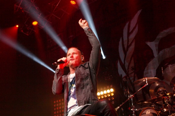Corey Taylor of Slipknot and Stone Sour performing live amid a red background.