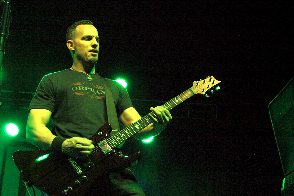 Mark Tremonti performs live amid dim green lighting.