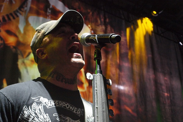 Aaron Lewis of Staind performing live amid yellow and orange lighting.