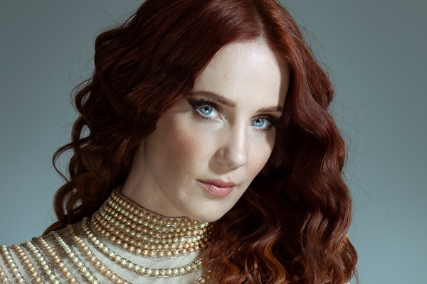 Epica vocalist Simone Simons posting with a beige collard shirt and bright, blue eyes. Epica's new album is 2021's 