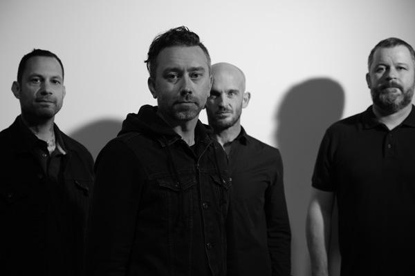 Rise Against pictured in black and white, featuring (from left to right) Joe Principe, Tim McIlrath, Zach Blair and Brandon Barnes.