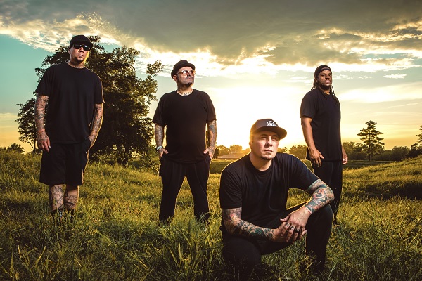 The members of P.O.D. stand outside in a green field in this press image.