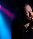 Jonathan Davis of Korn performing amid dark blue lighting.