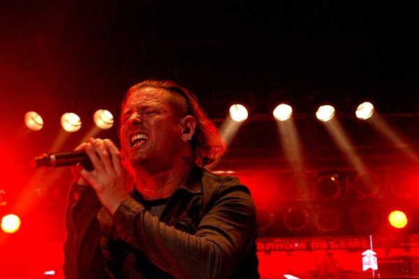 Corey Taylor of Stone Sour and Slipknot performing live amid a red-lit stage.