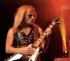 Photo of RIchie Faulkner of Judas Priest performing live amid red and yellow lighting.