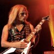 Photo of RIchie Faulkner of Judas Priest performing live amid red and yellow lighting.