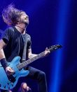 Dave Grohl of Foo Fighters performing amid a blue background and bright blue lights during a show in Detroit, Michigan.