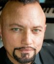 Geoff Tate sits in his studio in front of a grand piano.