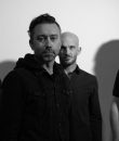 Rise Against pictured in black and white, featuring (from left to right) Joe Principe, Tim McIlrath, Zach Blair and Brandon Barnes.