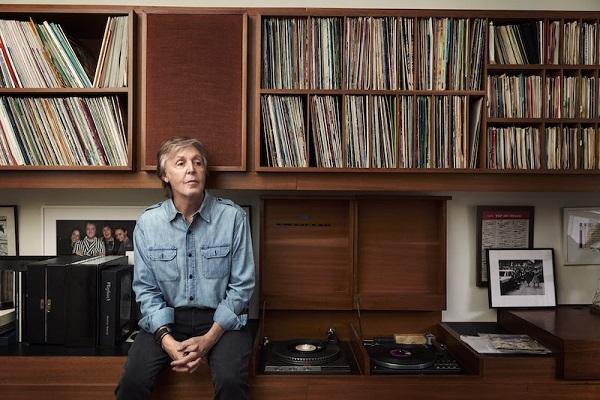 Photo of Paul McCartney sitting in a library.