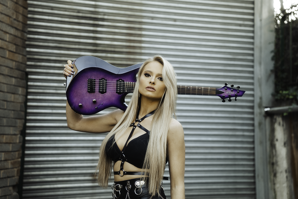 Machine Gun Kelly guitarist Sophie Lloyd posing with a purple guitar.