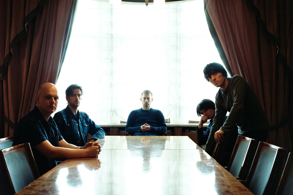 Image of the alternative rock band Radiohead sitting at a table.