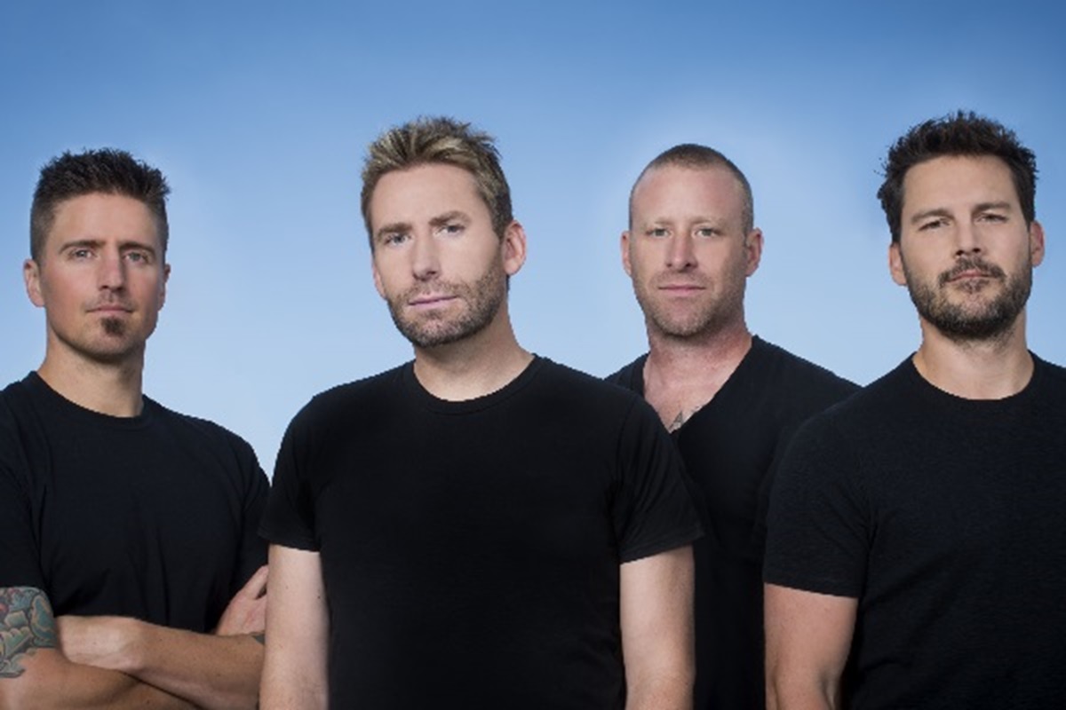 Rock band Nickelback standing with a blue background.