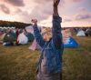 A young woman dancing at a fall music festival amid a sunset. Even though the summertime is known for its great music festivals, that doesn't mean you should overlook fall music festivals.