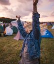 A young woman dancing at a fall music festival amid a sunset. Even though the summertime is known for its great music festivals, that doesn't mean you should overlook fall music festivals.
