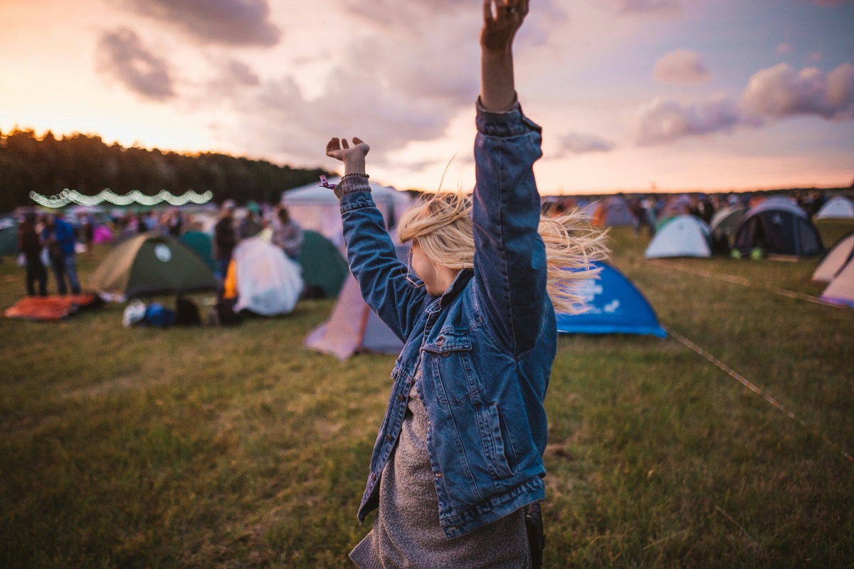 A young woman dancing at a fall music festival amid a sunset.