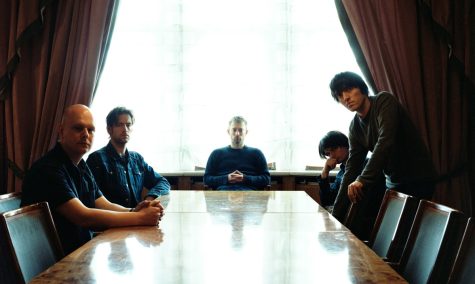 Image of a rock band at a table.