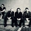 The rock band U2 sitting on a couch.