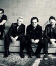 The rock band U2 sitting on a couch.