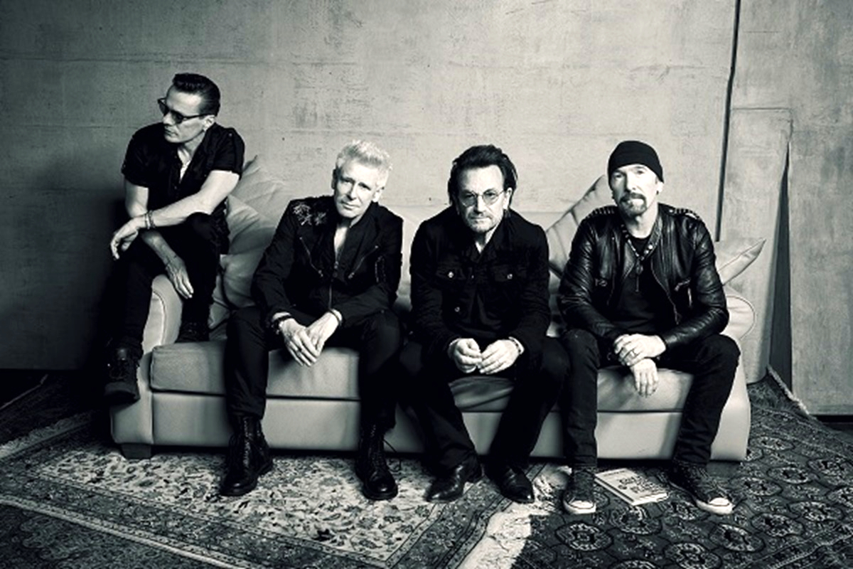 The rock band U2 sitting on a couch.